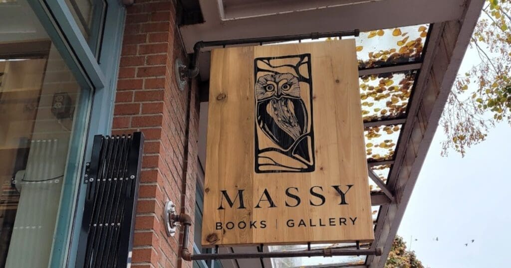 Wooden Massy Books Gallery sign with owl, outside this Indigenous-Owned Bookstore in Chinatown.